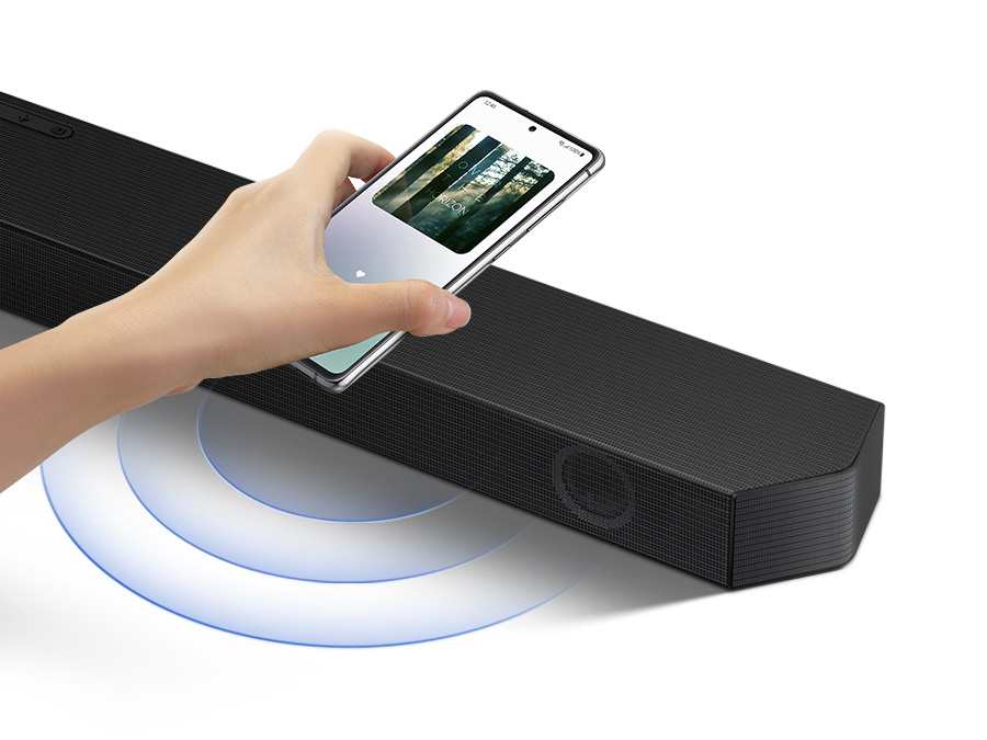 A hand taps a smartphone with the Samsung music app on-screen on the soundbar and the soundbar instantly plays music, showing how easy it is to switch from smartphone to soundbar.